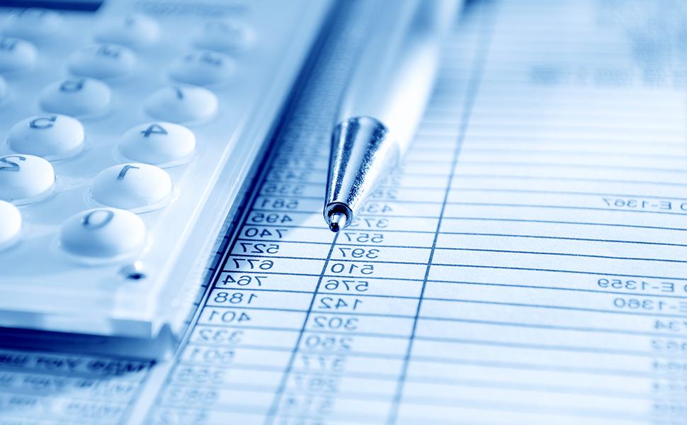 An image of a calculator and a pen atop a balance sheet
